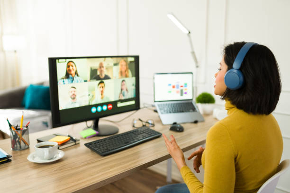 A consultant in headphones leading a video meeting from a home desk.