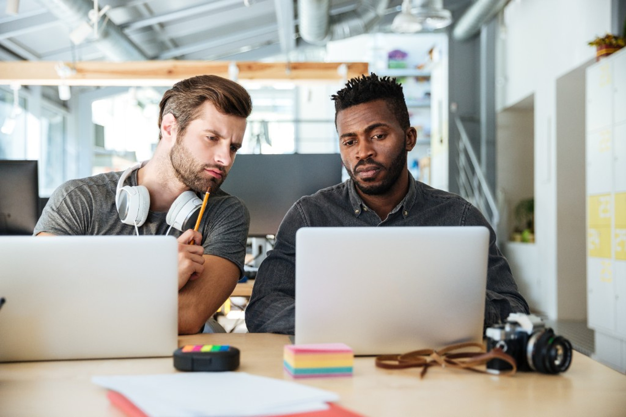 Two colleagues working together at laptops in a bright office.