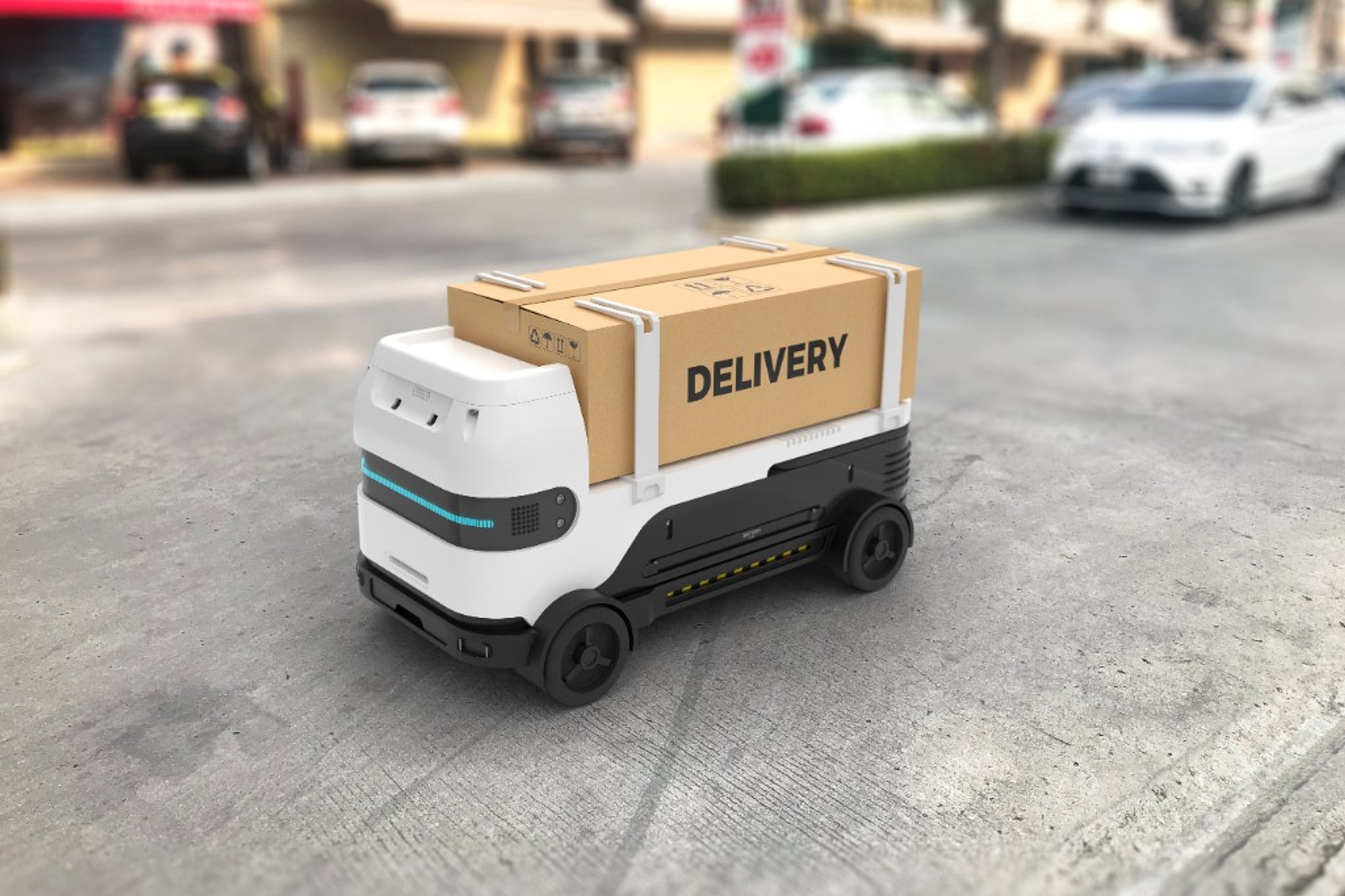 A small delivery robot carrying a box labeled DELIVERY along a street.